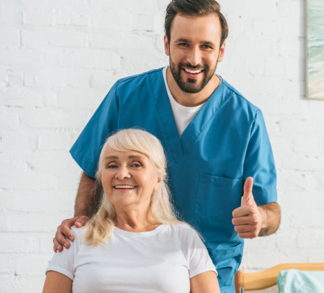 aide doing thumbs up and senior woman smiling